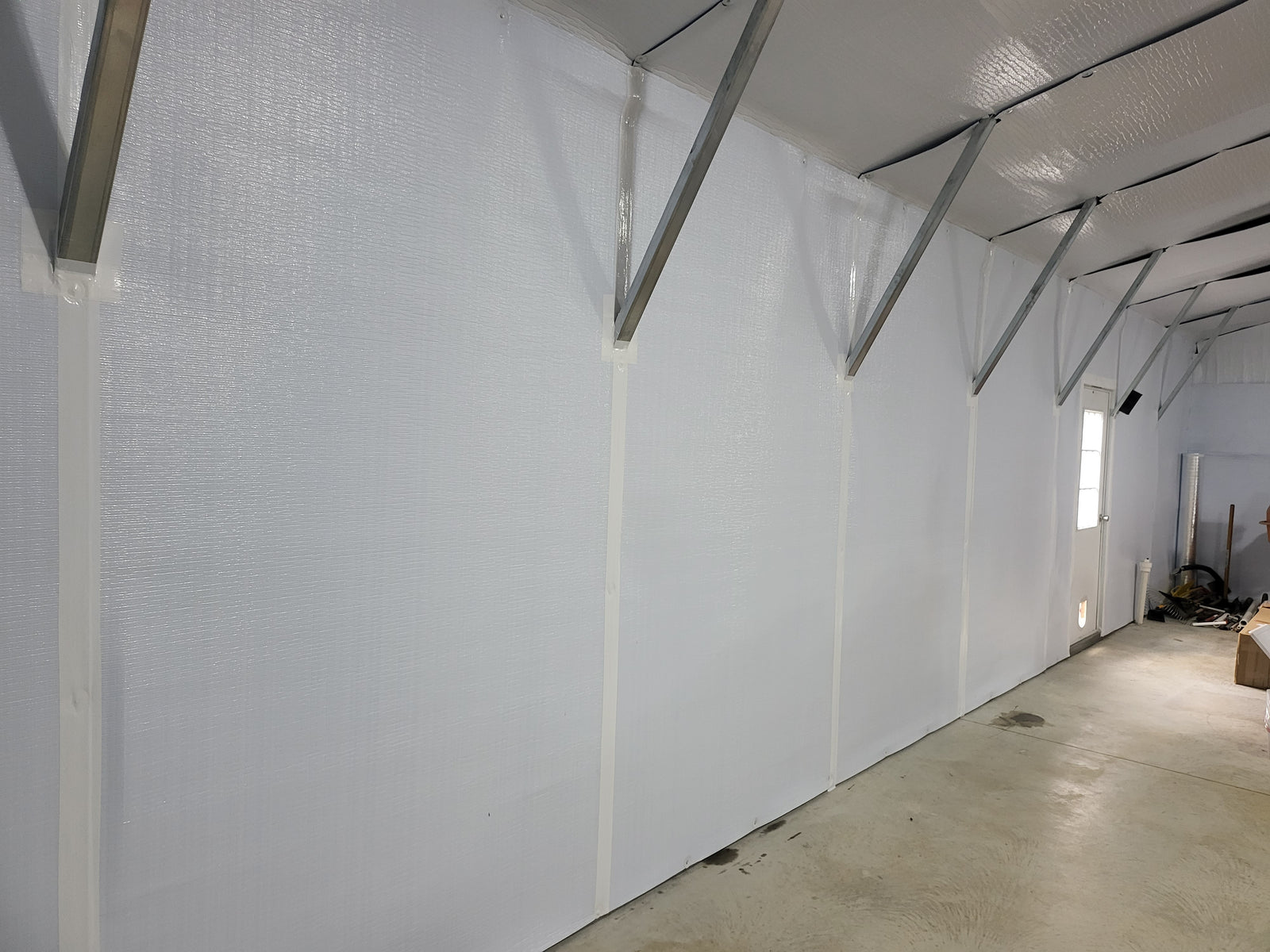 Arched-roof tubular steel building interior finished with BlueTex™ Insulation against the framing